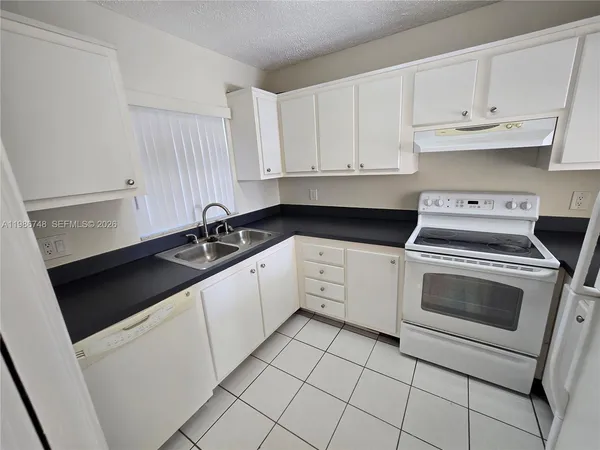 a kitchen with granite countertop white cabinets and white appliances