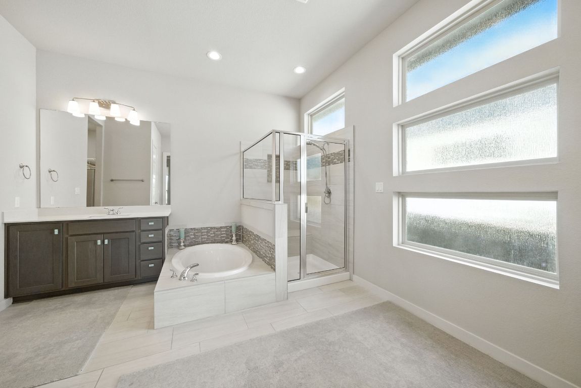437 Pienza Drive Georgetown, TX 78628 - Photo 21 of 32 a spacious bathroom with a granite countertop sink a toilet a mirror and a glass door shower