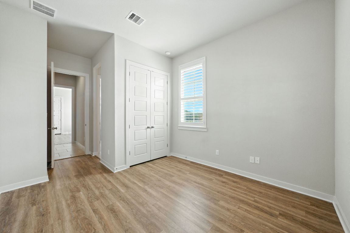 437 Pienza Drive Georgetown, TX 78628 - Photo 8 of 32 an empty room with wooden floor and windows