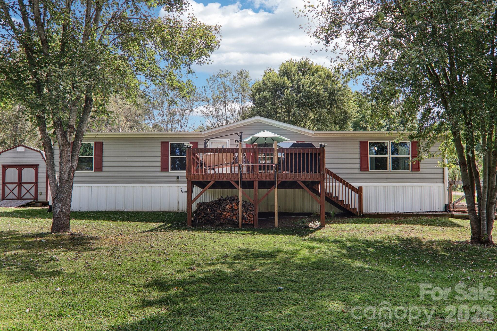 a house that has a big yard with wooden fence and some plants and trees