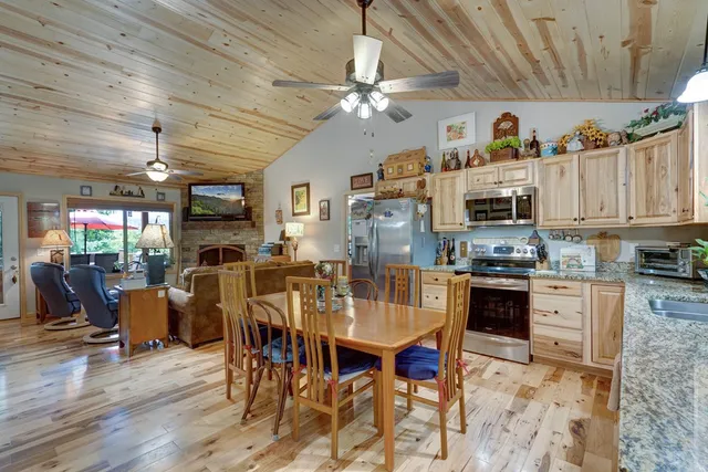 a kitchen with stainless steel appliances granite countertop a refrigerator a stove top oven a sink dishwasher and dining table with wooden floor