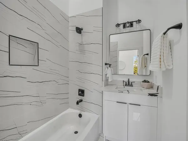 a bathroom with a bathtub sink and mirror