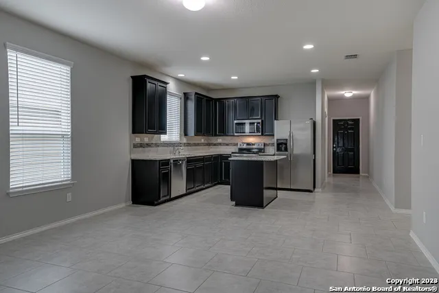 a kitchen with stainless steel appliances granite countertop a stove top oven a sink and a refrigerator