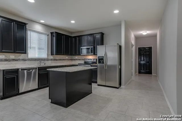 a kitchen with stainless steel appliances granite countertop a refrigerator and a stove top oven