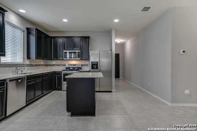 a kitchen with stainless steel appliances granite countertop a stove a sink and a refrigerator