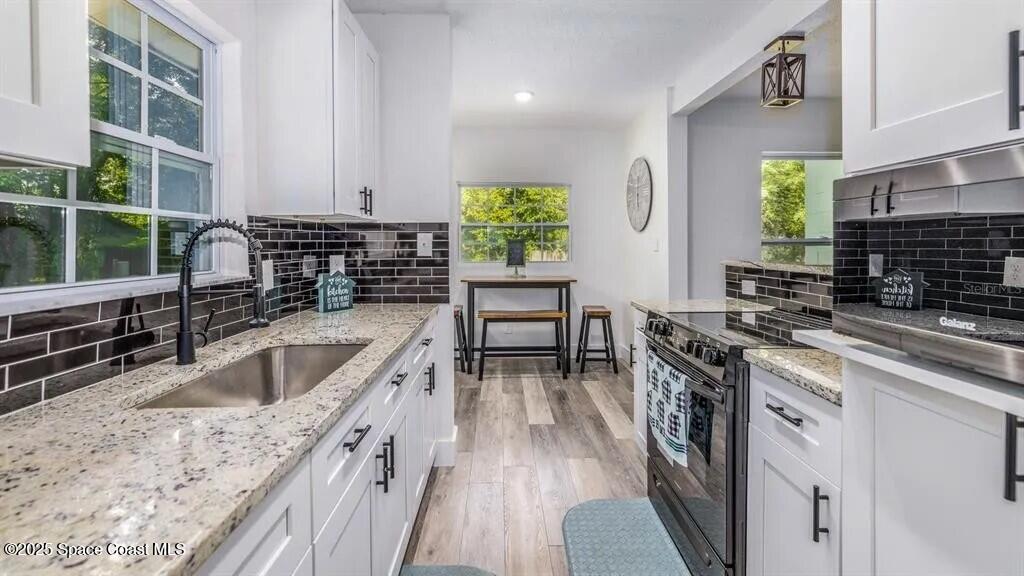 8812 Trevarthon Road Orlando, FL 32817 - Photo 4 of 22 a kitchen with stainless steel appliances granite countertop a sink a stove and a wooden floors