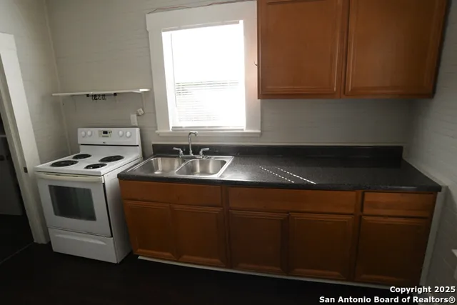 a kitchen with sink a microwave a stove and cabinets