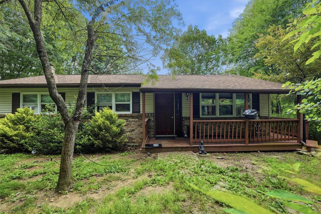 A charming exterior welcomes with a covered front porch and mature landscaping.