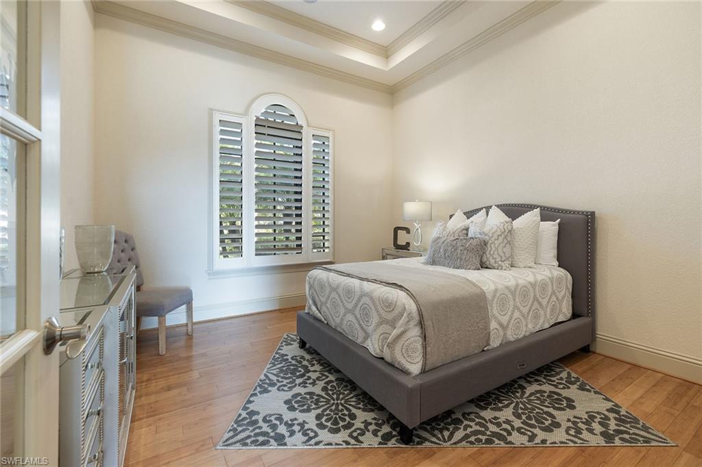 16540 Cellini Lane Naples, FL 34110 - Photo 22 of 50 a bedroom with a bed and a table with wooden floor