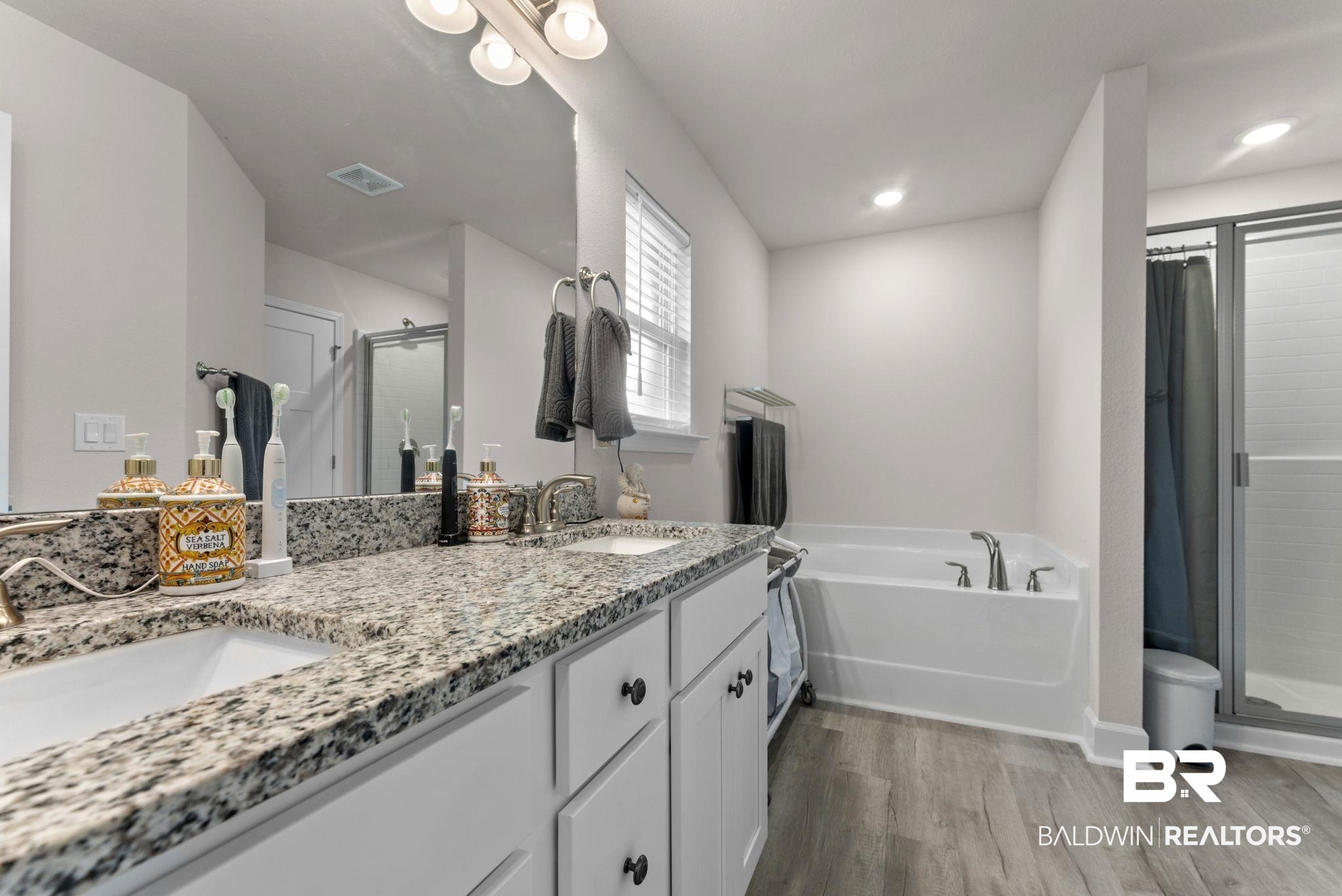 692 Mayflower Drive Foley, AL 36535 - Photo 27 of 40 Bathroom with double vanity, a stall shower, a garden tub, and light wood-style floors