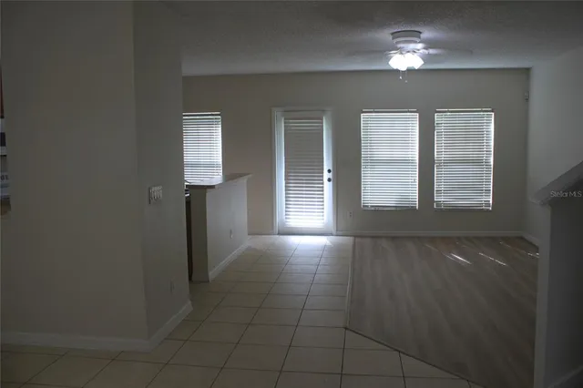 en empty room with windows and ceiling fan
