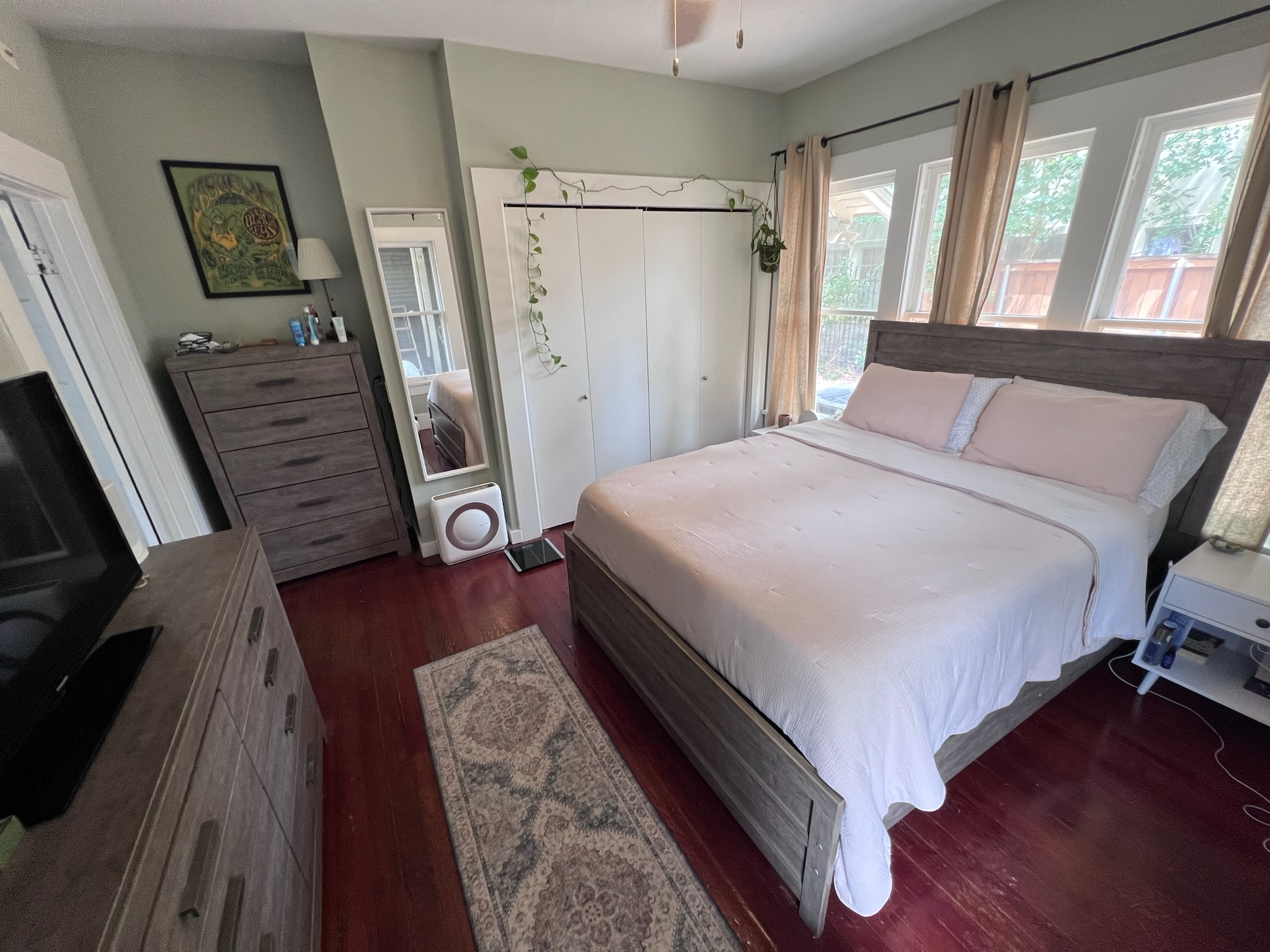 307 East 35th Street, Unit A Austin, TX 78705 - Photo 16 of 31 Natural light filters into this inviting bedroom through multiple windows, highlighting rich wood floors.