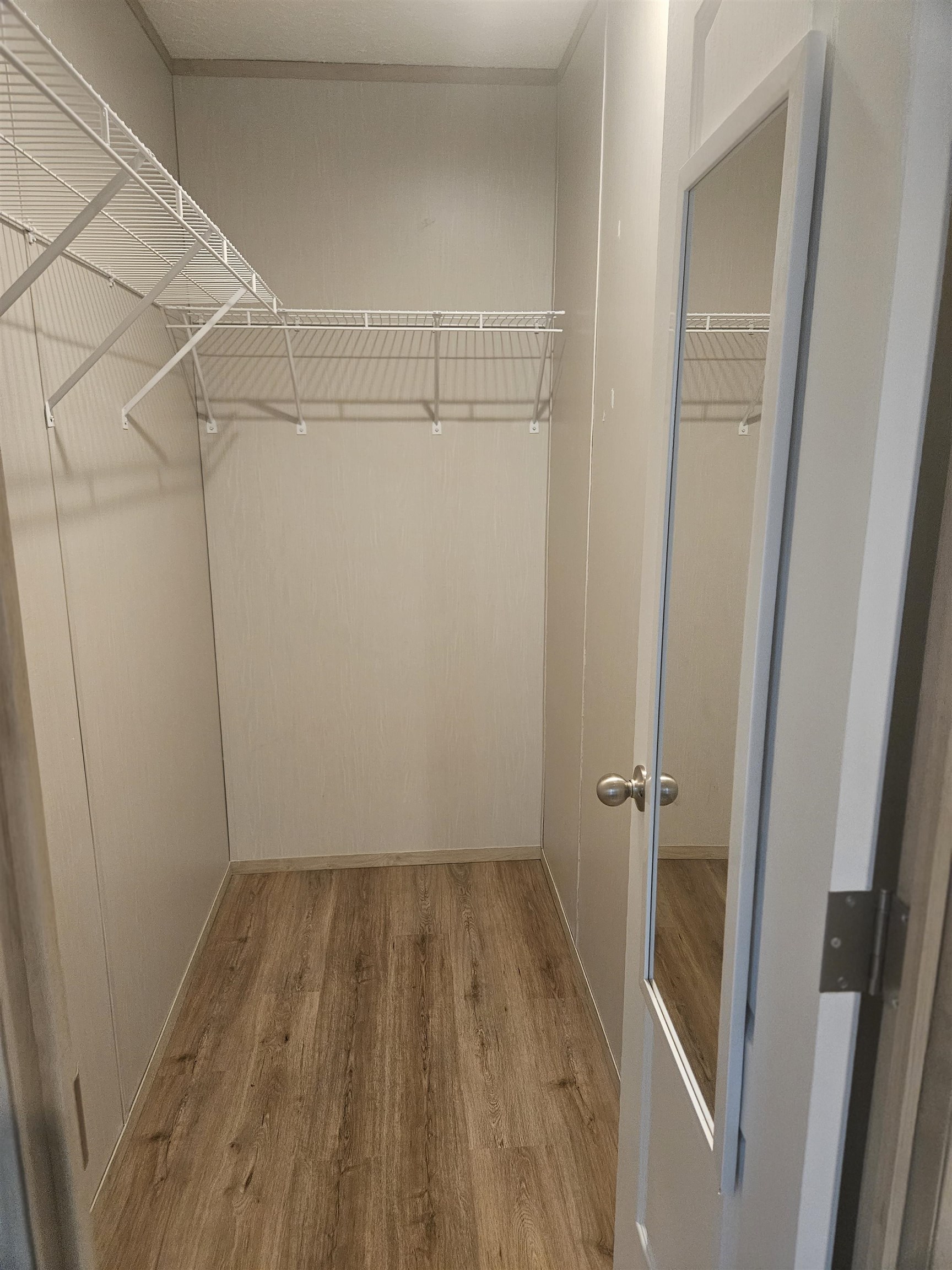 75 Pittman Road, Unit ROAD Somerville, TN 38068 - Photo 21 of 26 Walk-in closet featuring wood-finish flooring, white wire shelving, and a white door with an integrated full-length mirror