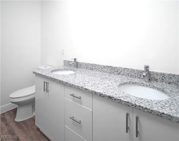 a bathroom with a granite countertop sink and a toilet