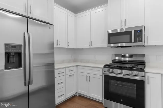 a kitchen with stainless steel appliances white cabinets and a stove top oven