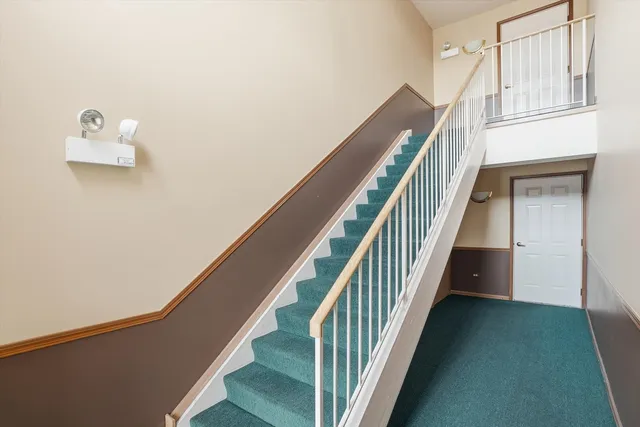 a view of staircase with lots of frames on wall and wooden floor