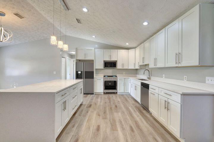 a large kitchen with granite countertop a large counter top a sink stainless steel appliances and cabinets