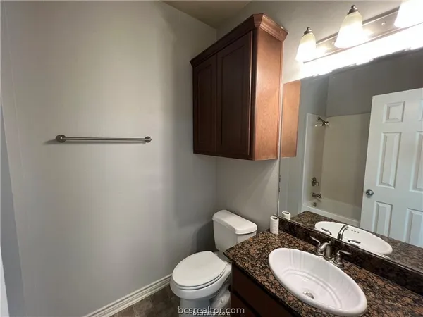 a bathroom with a granite countertop toilet sink and mirror