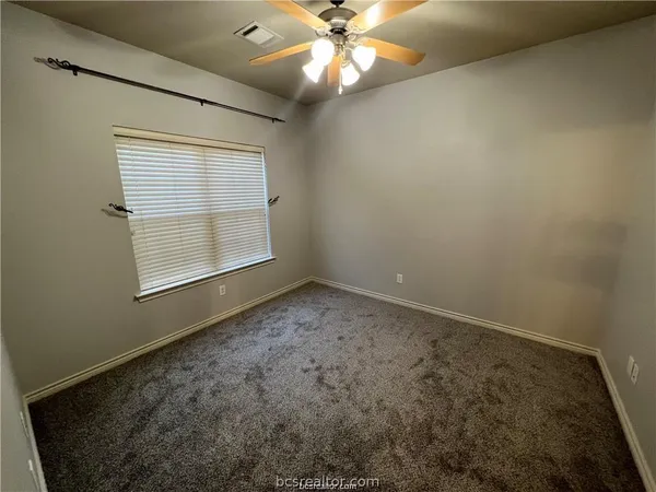 an empty room with a window and a ceiling fan