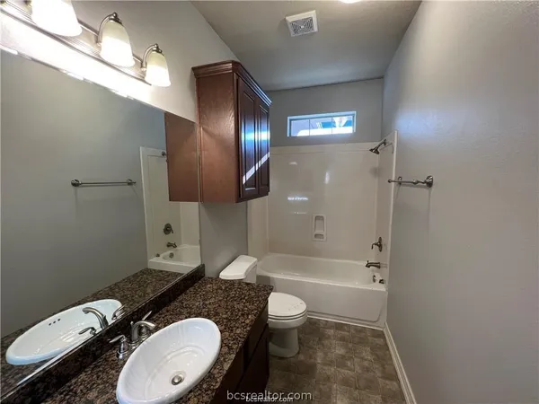 a bathroom with a granite countertop toilet a sink and bathtub