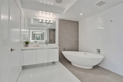 a spacious bathroom with a double vanity sink mirror and bathtub