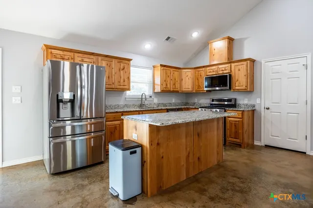a kitchen with kitchen island a counter top space cabinets stainless steel appliances and a window