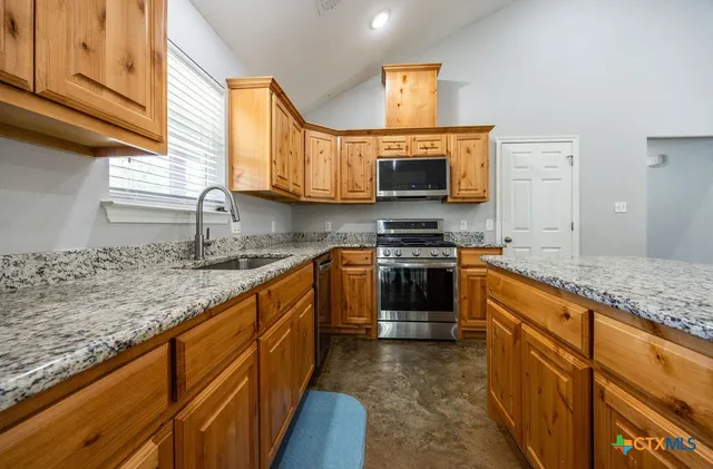 a kitchen with stainless steel appliances granite countertop a stove sink and a microwave