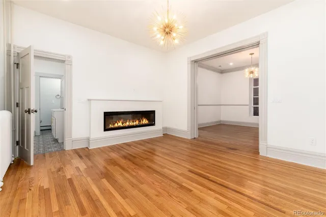 a view of kitchen and empty room with wooden floor