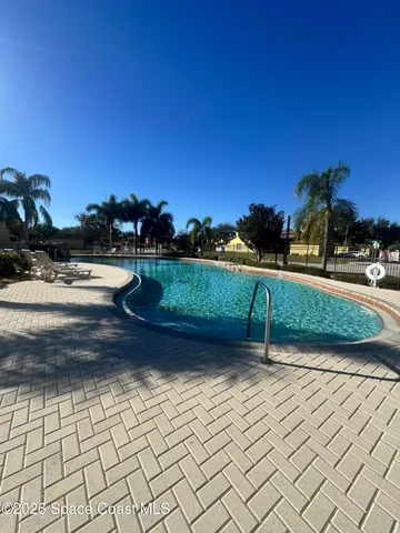 a view of swimming pool with outdoor seating and trees in the background