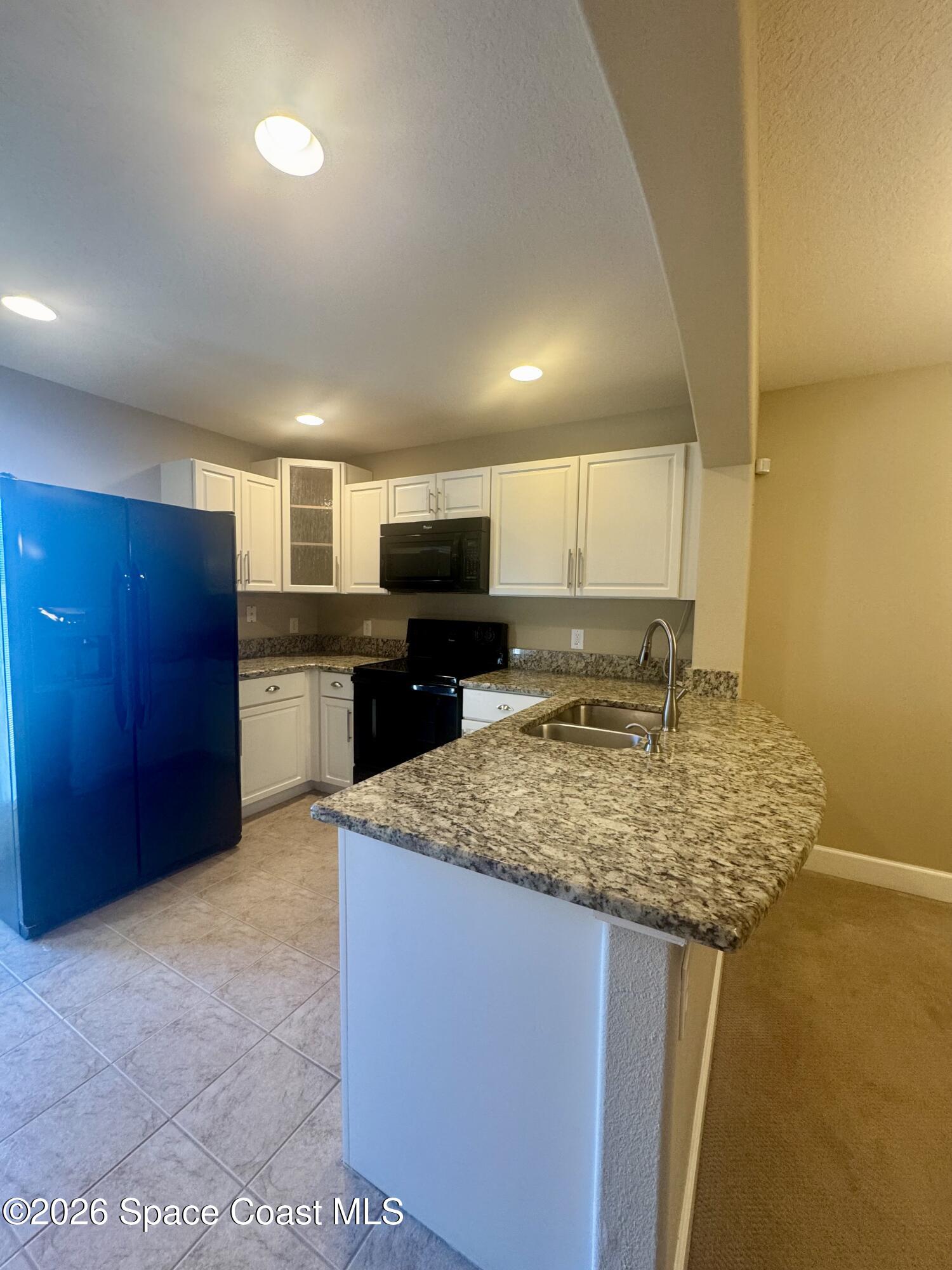4575 Radiant Way, Unit 102 Melbourne, FL 32901 - Photo 43 of 73 a kitchen with stainless steel appliances granite countertop a sink stove and refrigerator