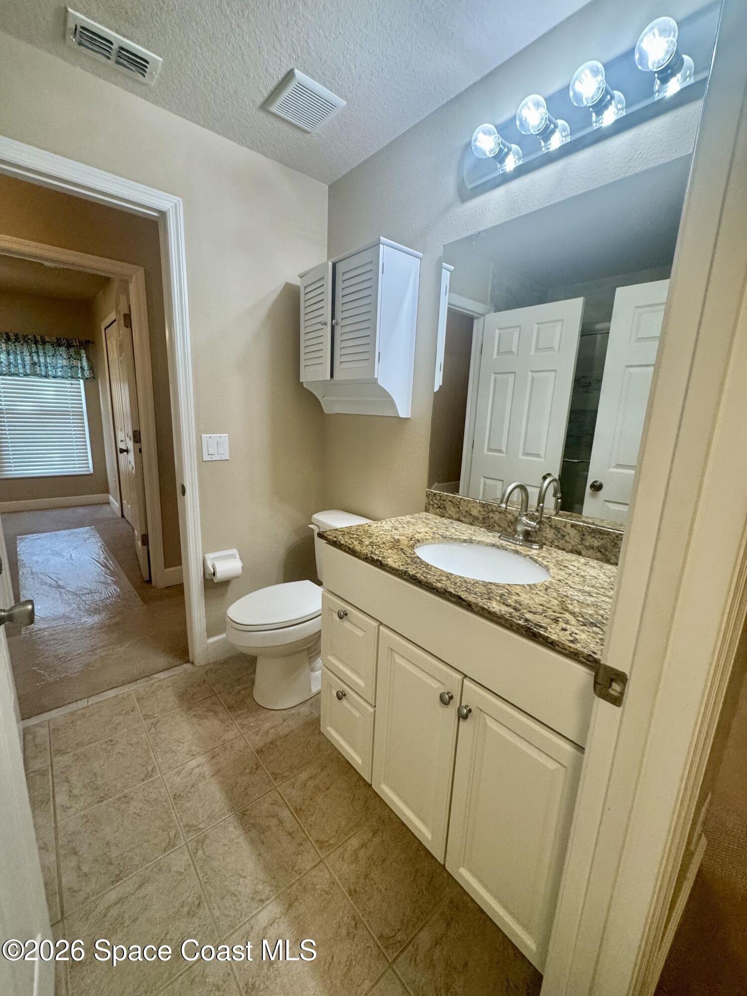 4575 Radiant Way, Unit 102 Melbourne, FL 32901 - Photo 51 of 73 a bathroom with a granite countertop sink a toilet and a mirror