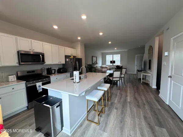 a view of kitchen with cabinets wooden floor and stainless steel appliances