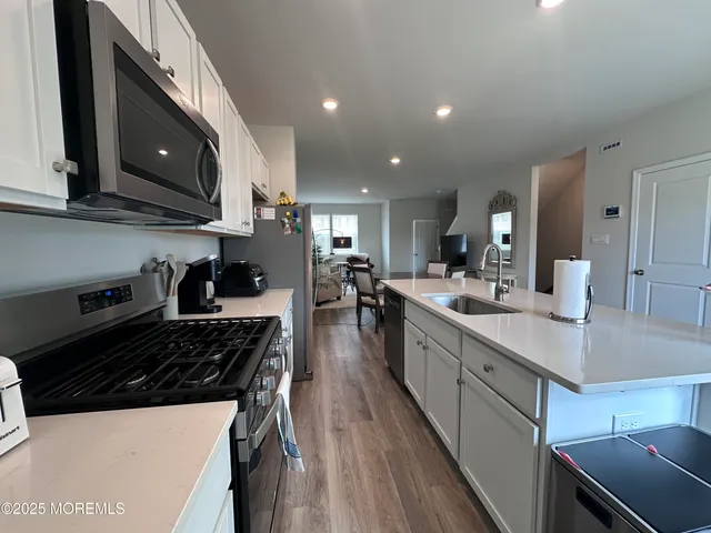 a kitchen with stainless steel appliances a sink a stove a microwave a center island and cabinets