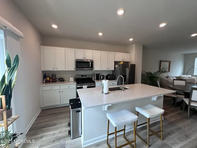 a kitchen with sink a refrigerator and chairs