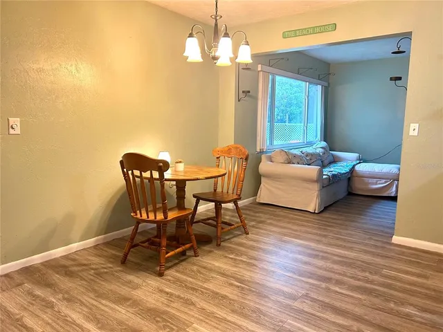 a dining room with wooden floor a chandelier a glass table and chairs