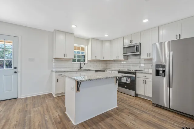 a kitchen with kitchen island granite countertop a sink cabinets and stainless steel appliances