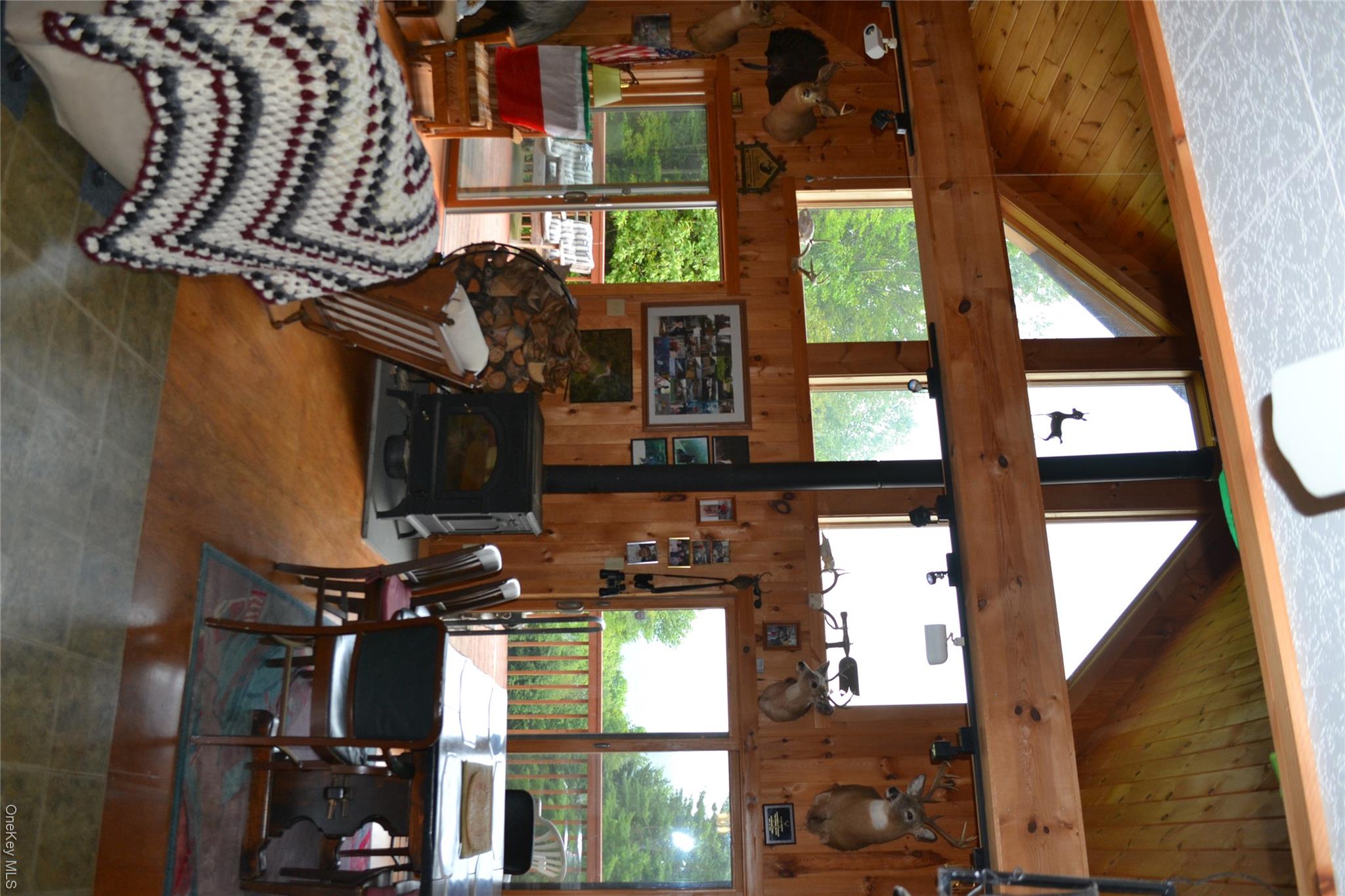 365 Via Appian Way Roscoe, NY 12776 - Photo 10 of 30 Tiled dining space with a wood stove, wooden walls, a wood ceiling with exposed beams, and high vaulted ceiling
