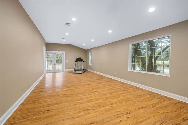 a view of an empty room with wooden floor and a bathroom