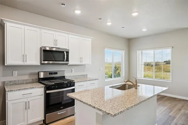 a kitchen with granite countertop a sink a stove and cabinets