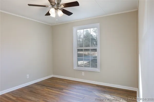 an empty room with wooden floor chandelier fan and windows