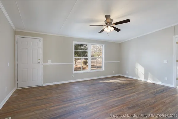a view of empty room with wooden floor and fan