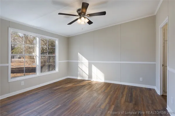 a view of empty room with wooden floor and fan
