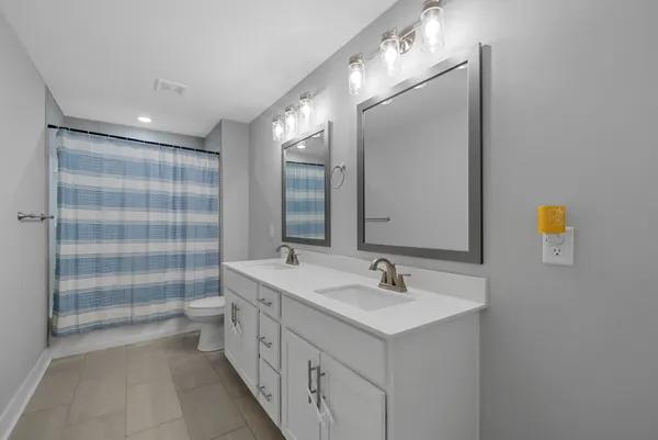 a bathroom with a double vanity sink a toilet and shower