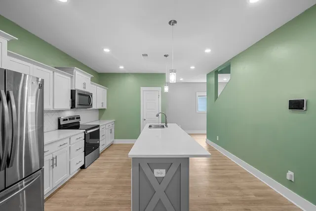 a large kitchen with stainless steel appliances granite countertop a sink a stove top oven and a refrigerator