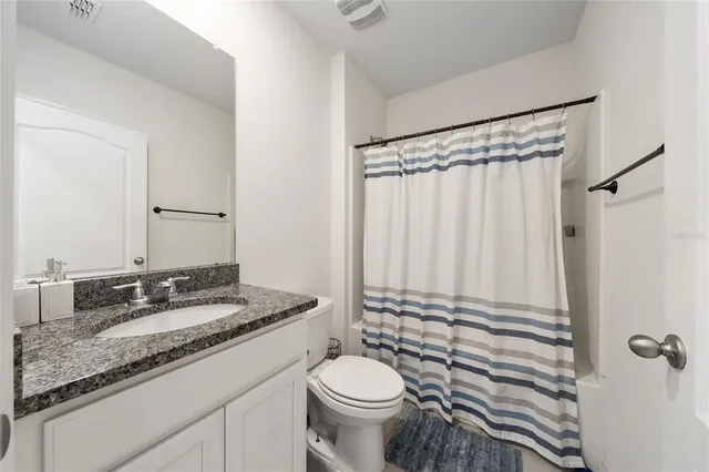 a bathroom with a granite countertop sink toilet and shower