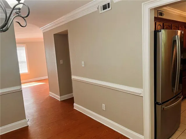 a view of a refrigerator in kitchen and an empty room