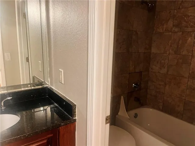 a bathroom with a granite countertop sink and a bathtub