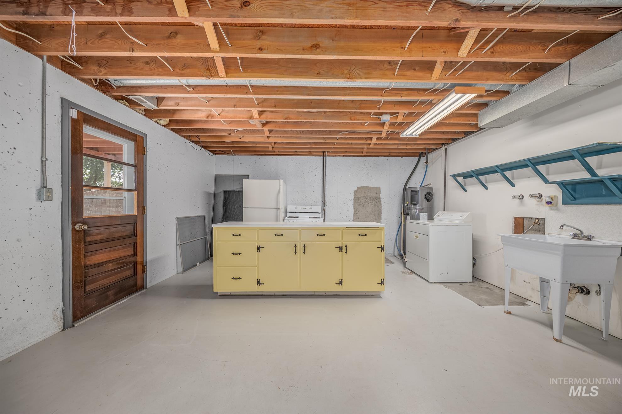 1493 Cove Road Weiser, ID 83672 - Photo 34 of 50 Utility space featuring exposed ceiling joists, a wooden exterior door with glass panels, a freestanding utility sink, and built-in wall shelving