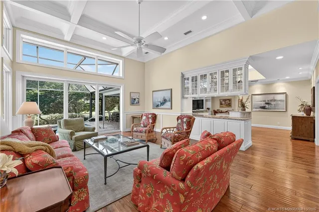 a living room with furniture a large window and wooden floor