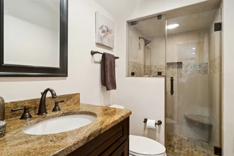 a bathroom with a granite countertop sink toilet and shower